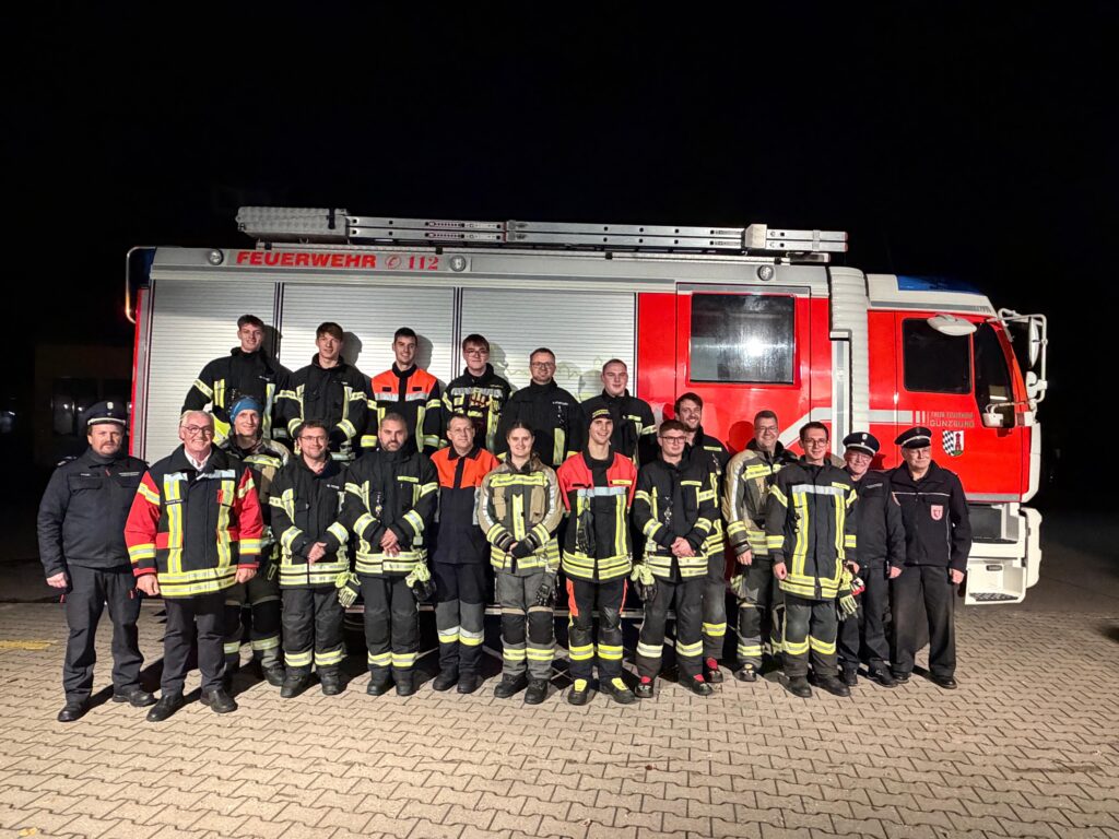 Auf dem Bild sind die erfolgreichen Teilnehmer, inklusive der Schiedsrichter vor einem Feuerwehrfahrzeug.